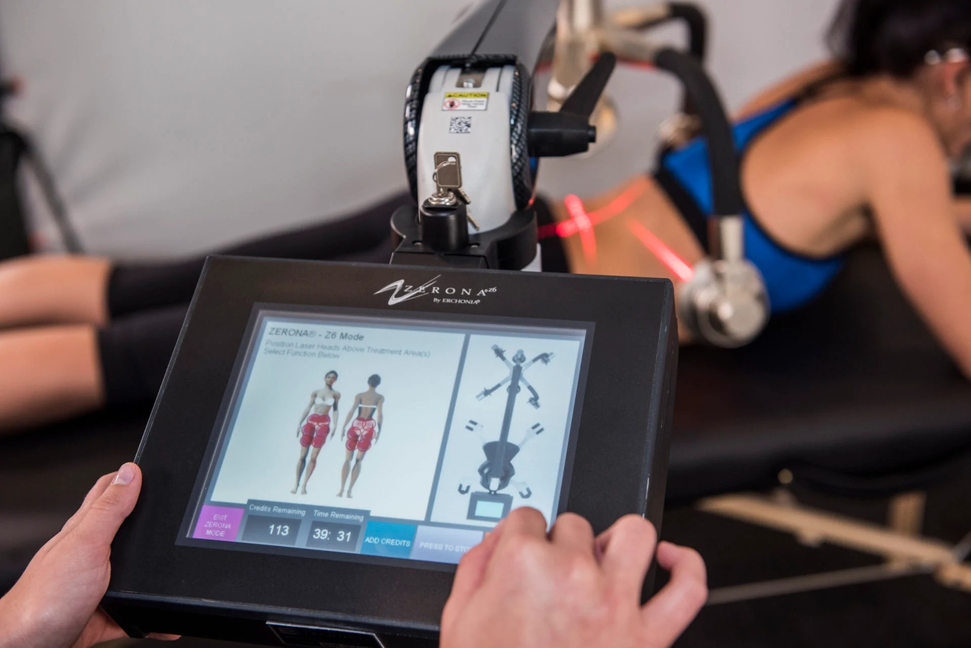 Patient receiving Zerona Z6 laser body contouring treatment with a therapist monitoring the device